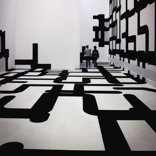 Immersive black and white geometric installation with curved and angular shapes on floor and walls, visitors exploring the space, Berlin gallery