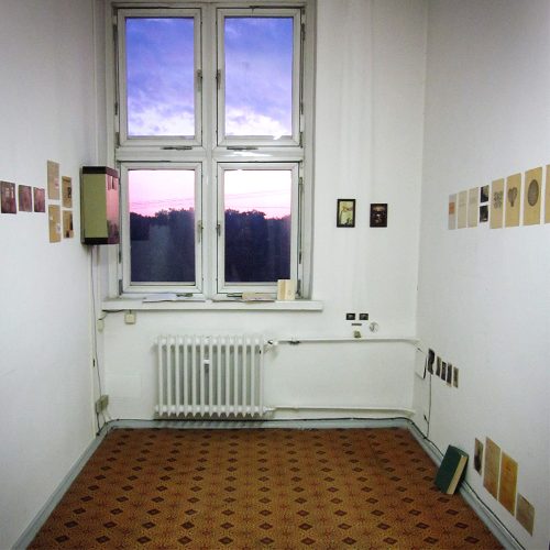 Minimalist studio space with large windows overlooking twilight sky, framed artworks on white walls, Berlin