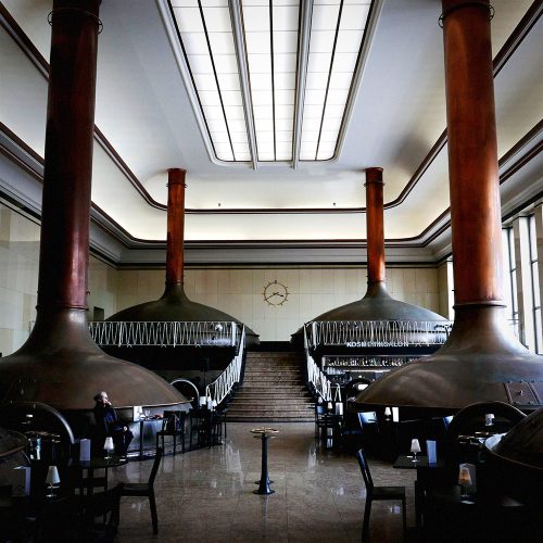 Modernist interior with symmetrical copper vessels, red columns, and geometric ceiling design, Berlin
